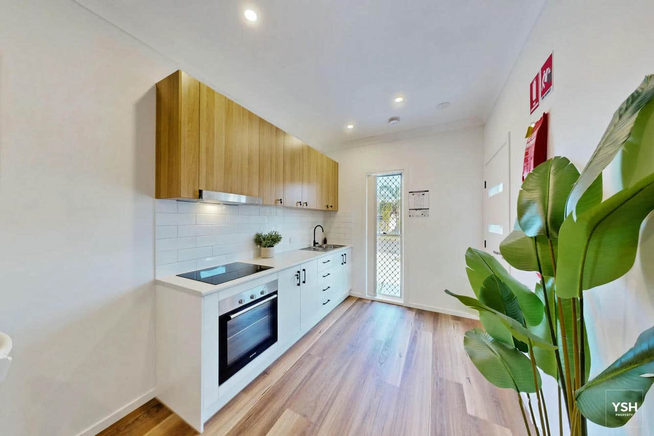 Shared Kitchen – Modern Rooming House Interior Modern shared kitchen area in rooming house – white cabinetry, timber finishes and natural lighting ideal for co-living environments.